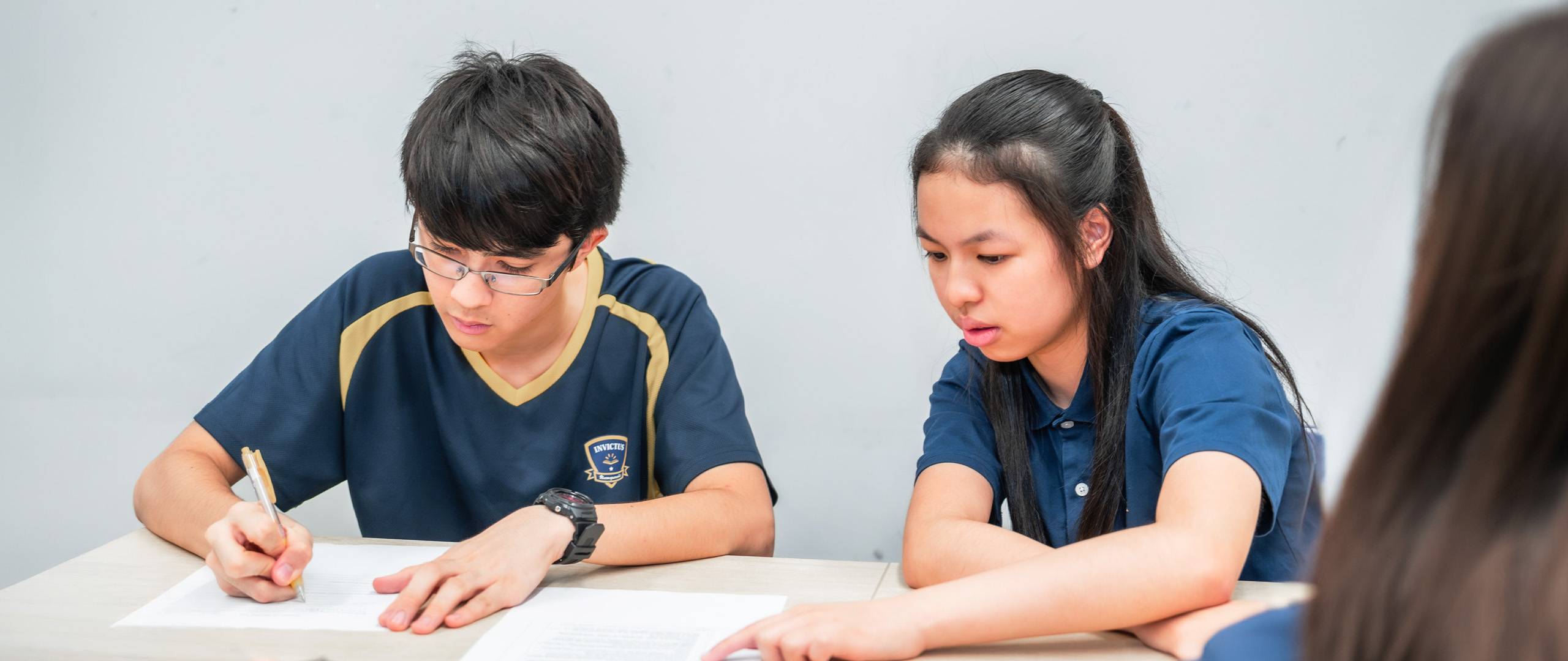 Secondary school students at Invictus School Hong Kong working together on written assignments, focused and engaged in a classroom setting.