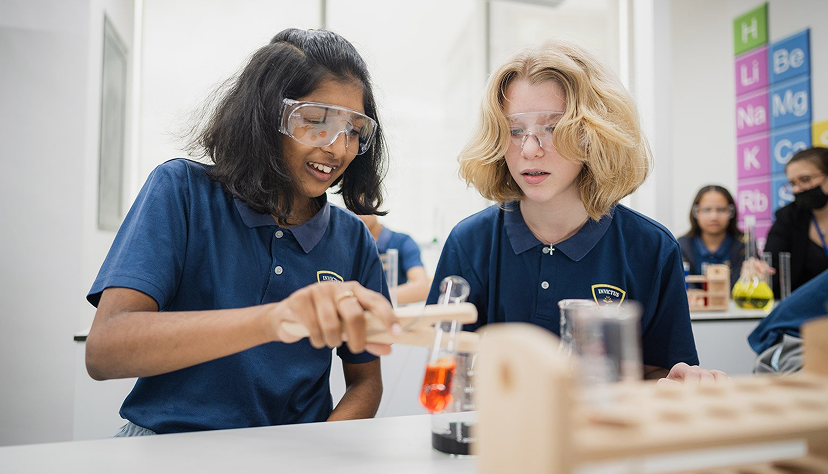 Secondary Invictus students conducting a science experiment with lab equipment in class.