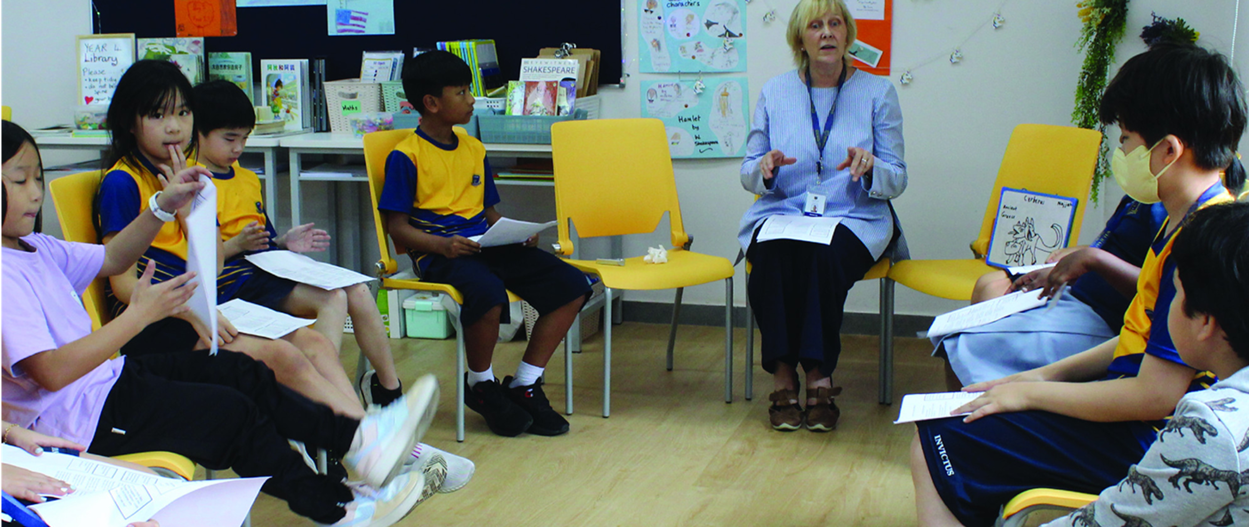 Primary students and a teacher in a collaborative reading or discussion circle at Horizon Hills Invictus International School Malaysia, engaged in active learning.