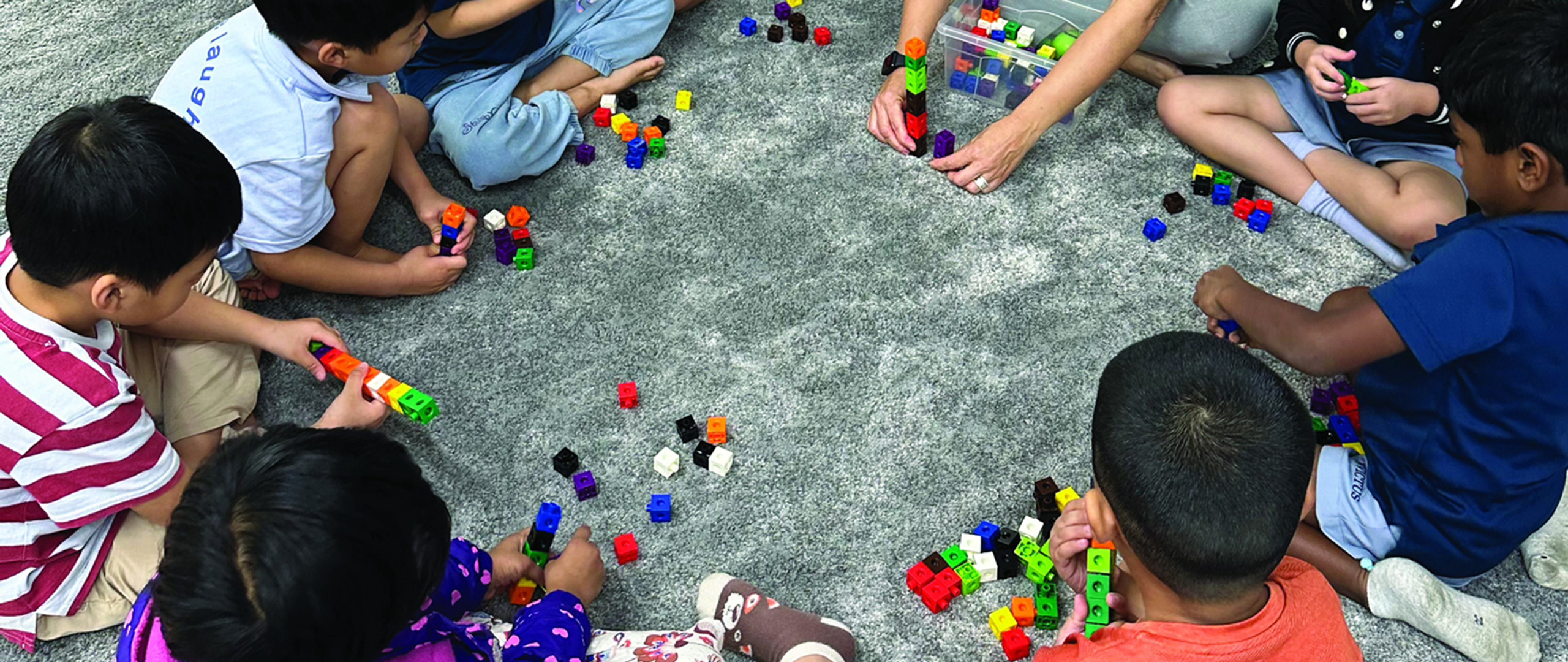 Young students at Horizon Hills Invictus International School Malaysia sitting in a circle and engaging in a hands-on maths activity using colourful interlocking cubes.
