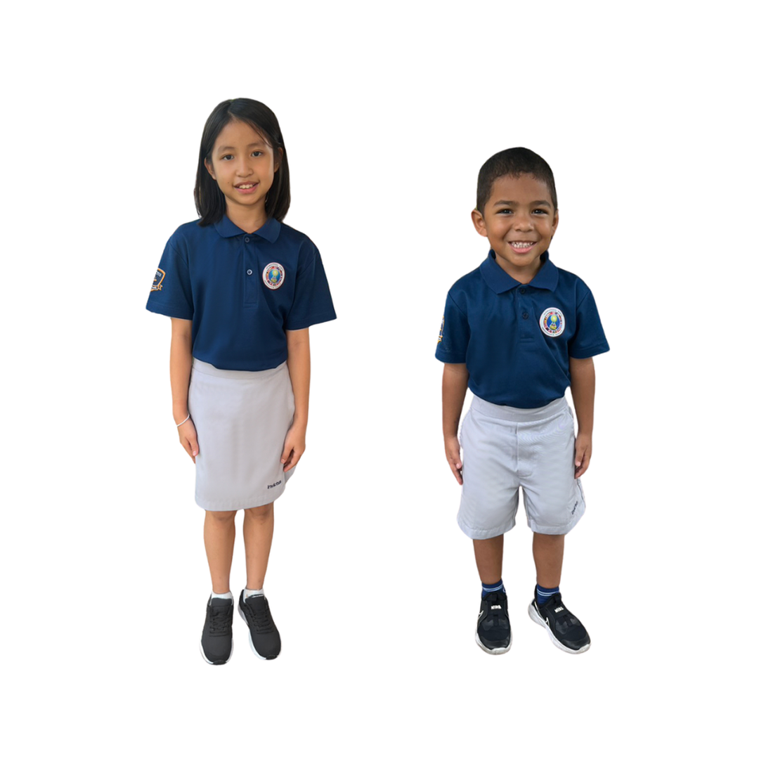 Invictus International School Thailand students in standard school uniforms; a young girl wears a navy polo with school logo and a grey skirt, while a younger boy wears the same navy polo paired with grey shorts, both smiling proudly against a white background.