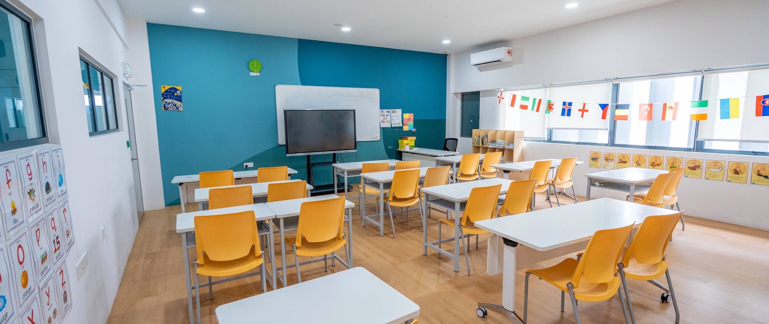 Modern classroom with yellow chairs, international flags, and smartboard.