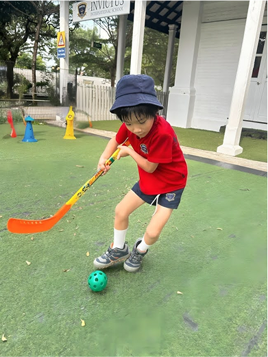 Student practising field hockey during a sports ECA on campus at Invictus International School.