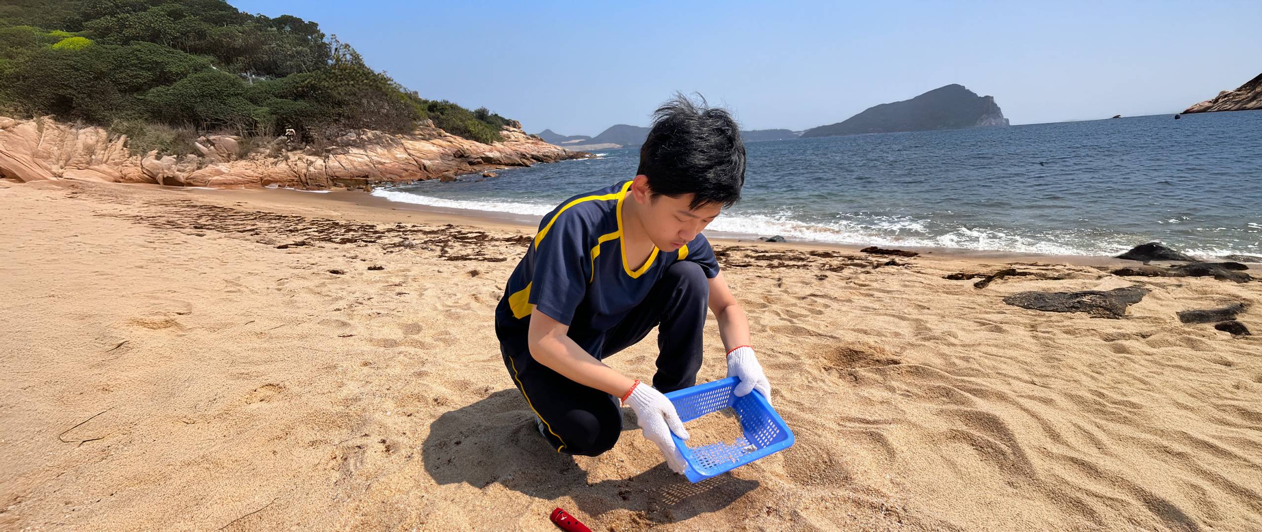 A young student cleaning the beach