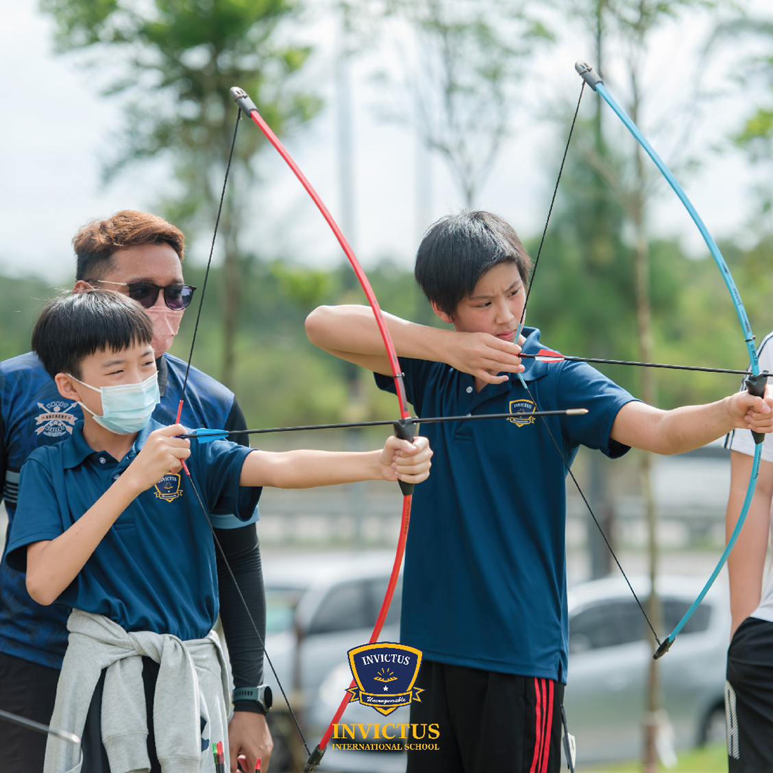 2 Invictus students and coach practicing archery