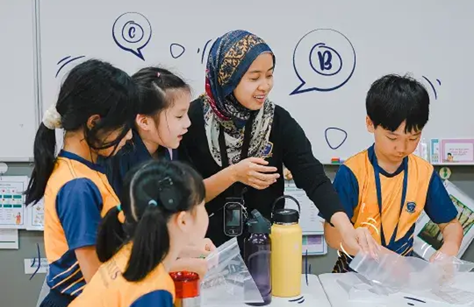 Primary students gather around a teacher during a hands-on science activity, engaging in group discussion and observation at Invictus International School.