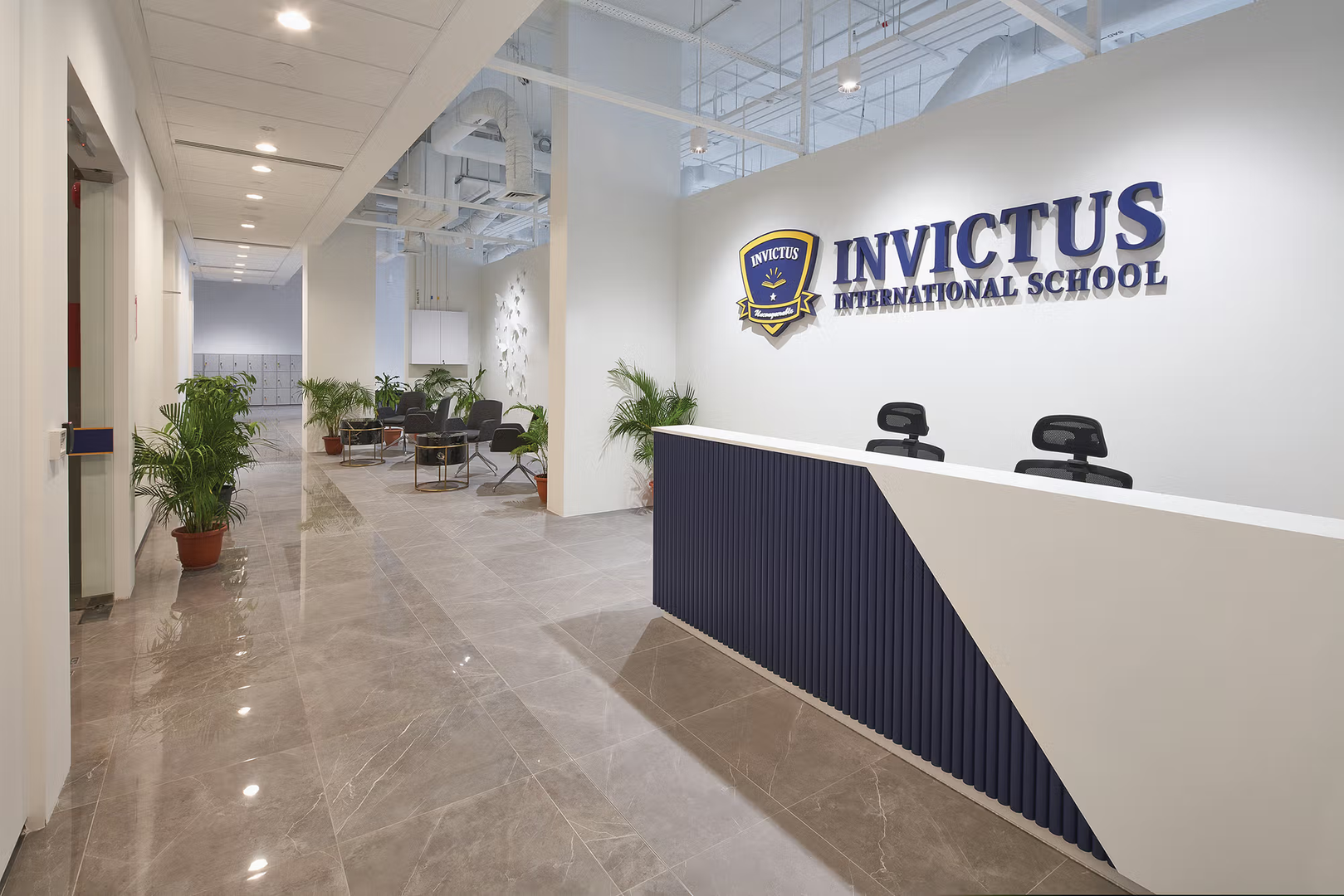 Reception area of Invictus International School's Centrium Square Campus in Singapore, featuring a modern front desk, school logo on the wall, indoor plants, and a contemporary waiting lounge.