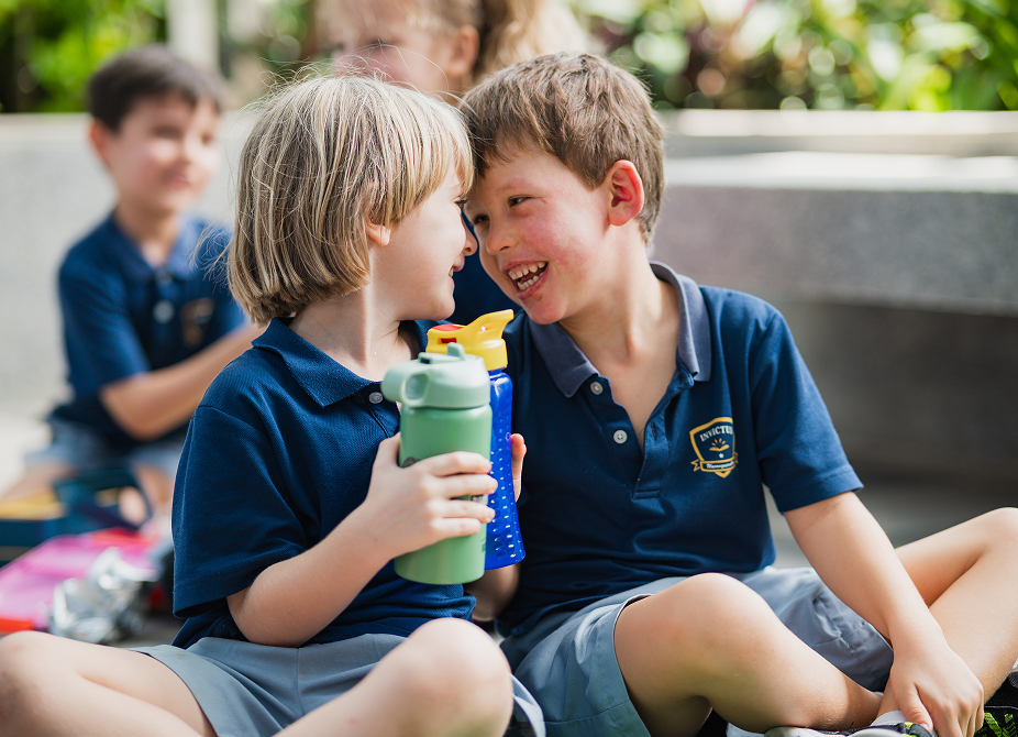 Two young invictus students laughing and sharing a moment outdoors.