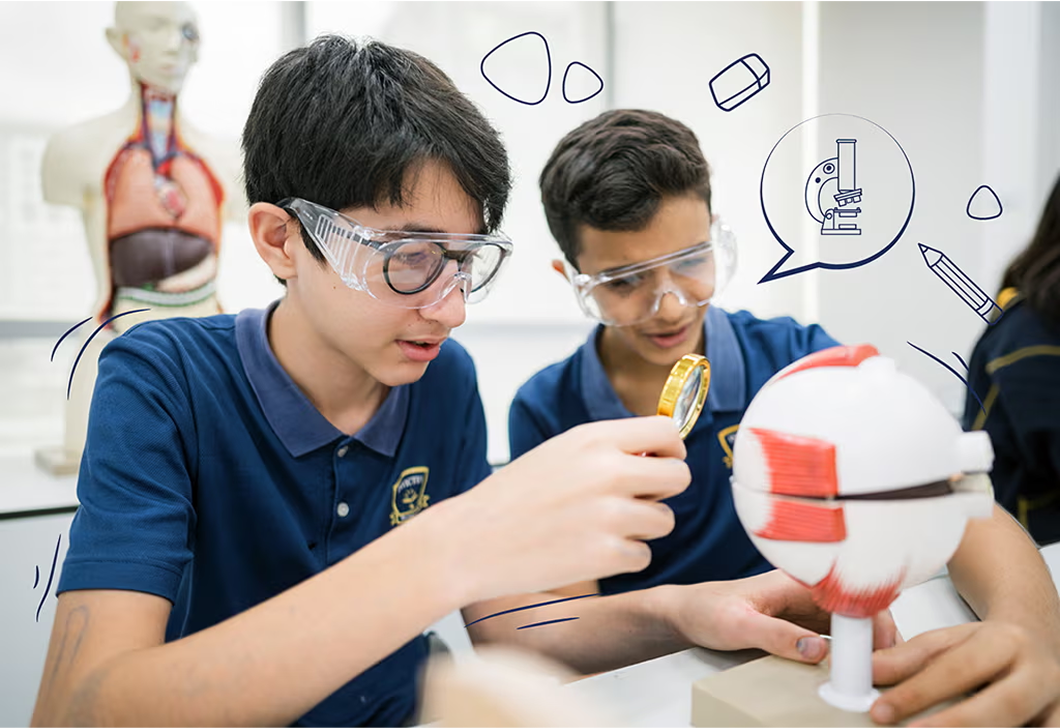 Two Invictus secondary students conducting a science experiment with anatomical models, wearing protective goggles and using magnifying tools.