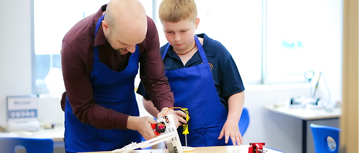 Teacher aiding student in a carpentry engineering project