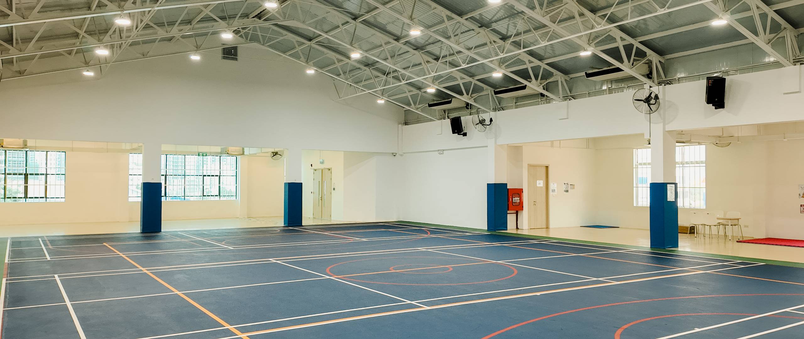 Spacious multi-purpose sports hall with marked courts and high ceilings for school events and physical education activities at Invictus Phnom Penh.