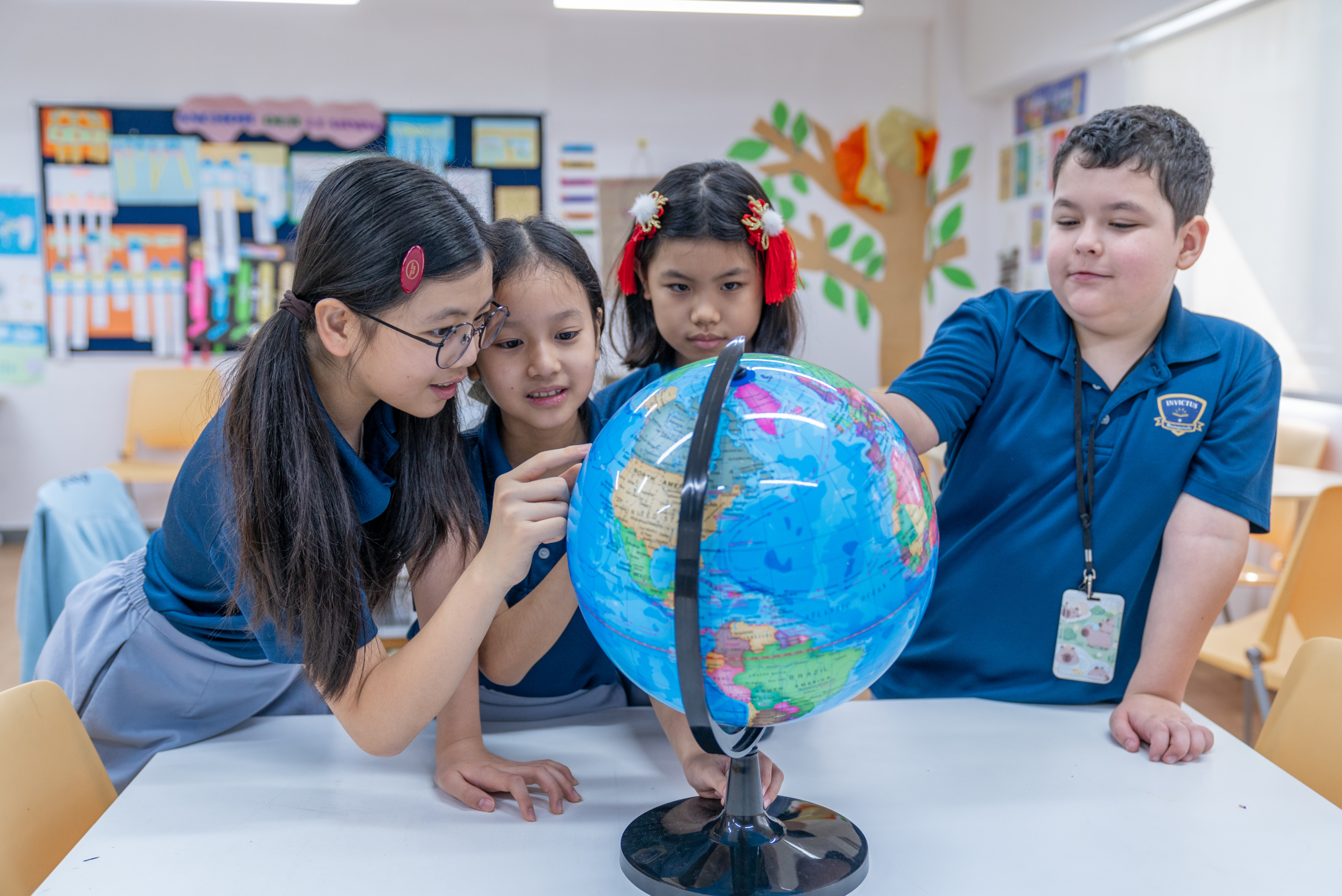 Students pointing at and interacting with globe