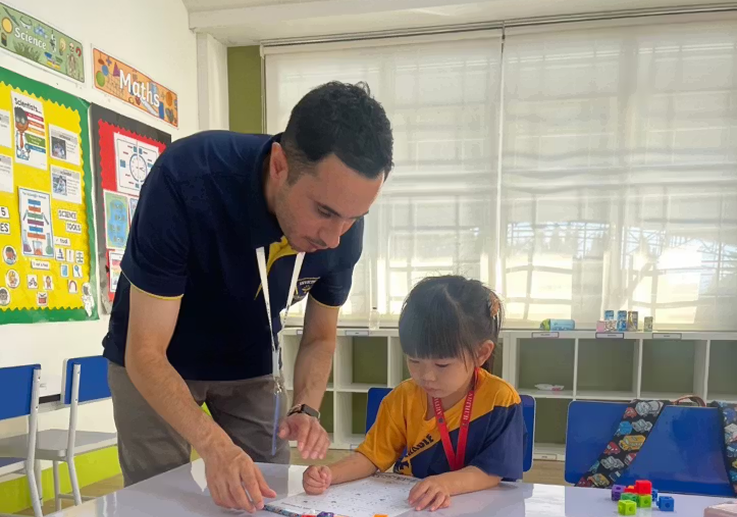 Teacher aiding young student to play blocks