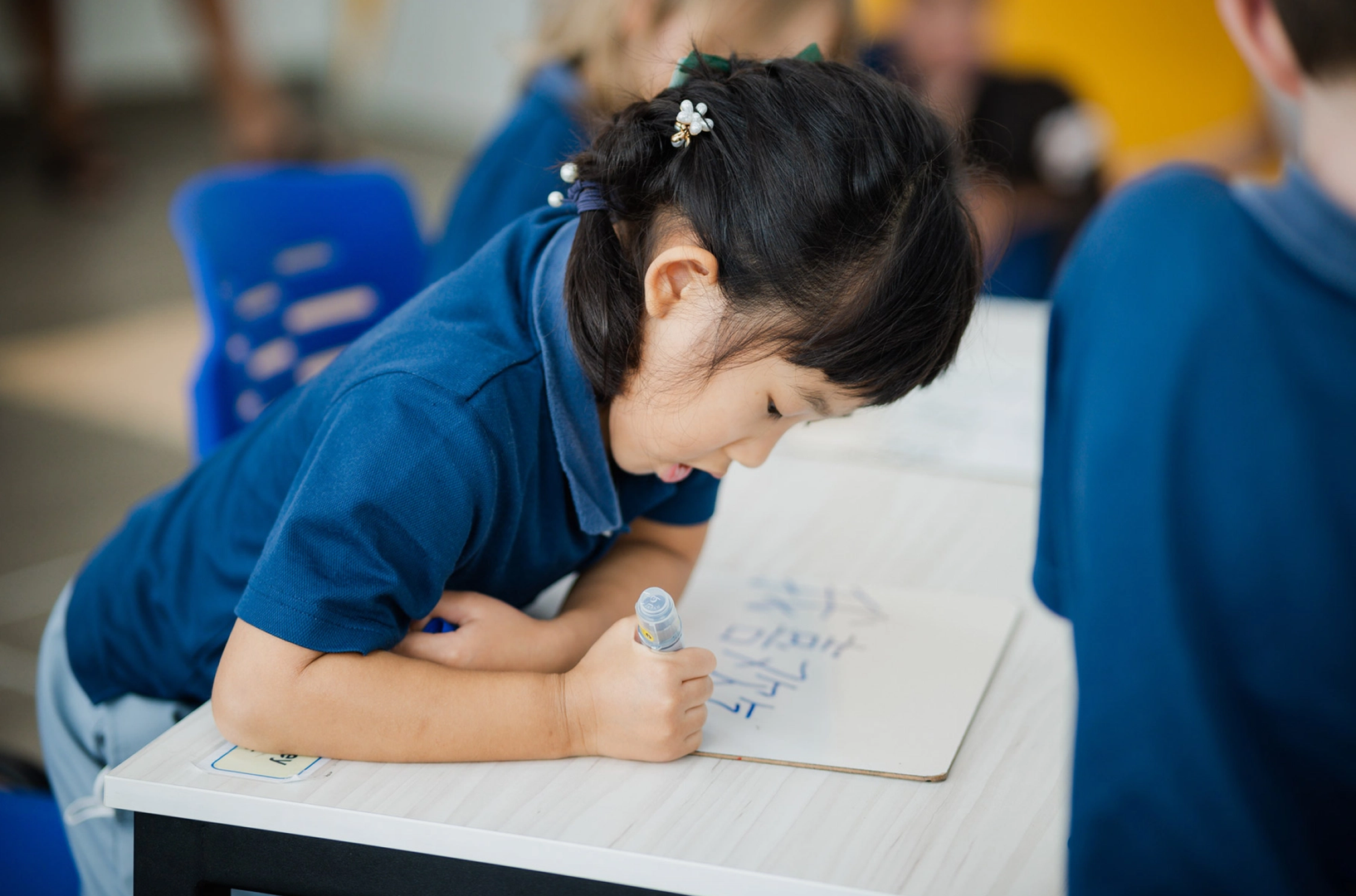Young student writing Mandarin characters in class
