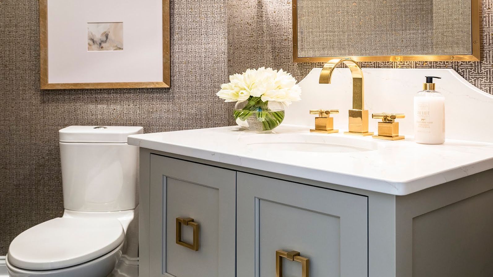 Bathroom with gray furniture vanity and gold accents.