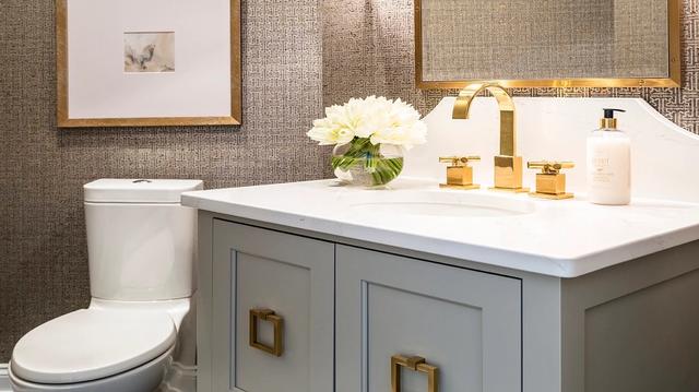 Bathroom with gray furniture vanity and gold accents by Dana Snyder