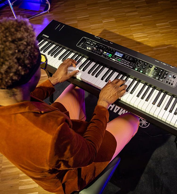 Over shoulder of man sitting and playing Yamaha keyboard