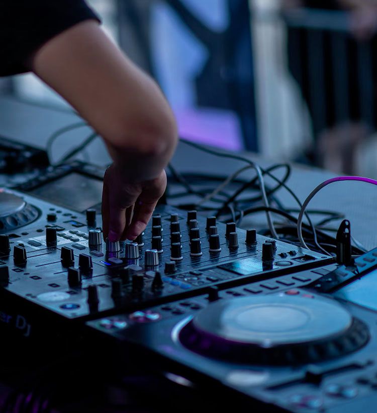 DJ performing turning knobs on synth with cables coming out the back