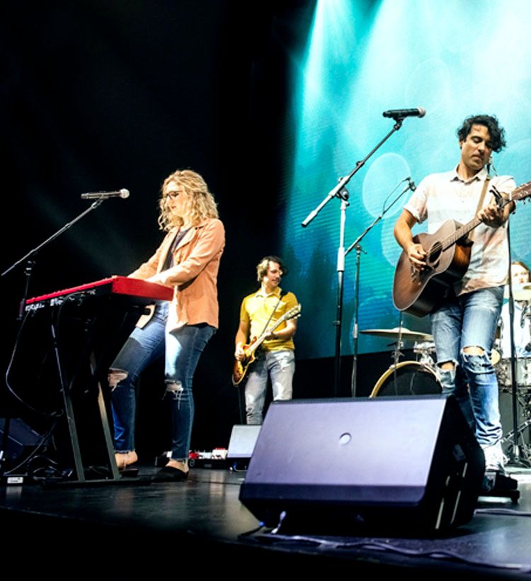 Band playing on stage with QSC speaker in foreground