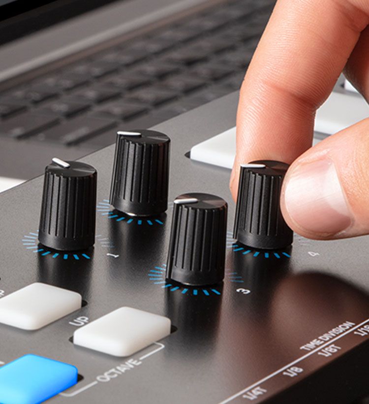 Close up of man's fingers turning knob on Alesis synth