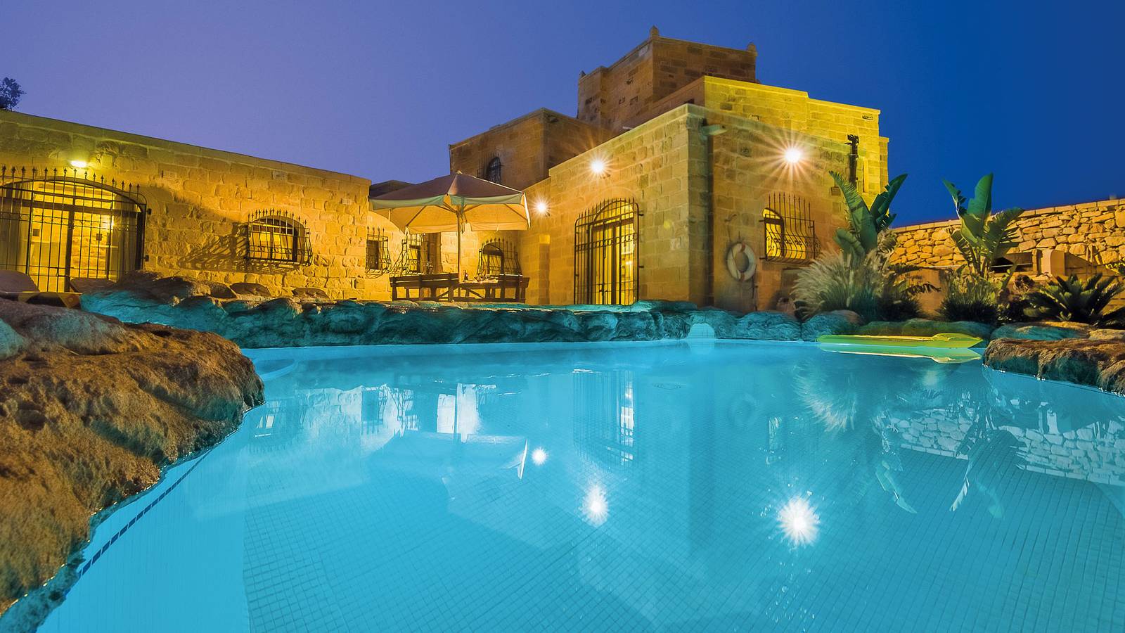 The Chateau's lake-style pool lit up at dusk