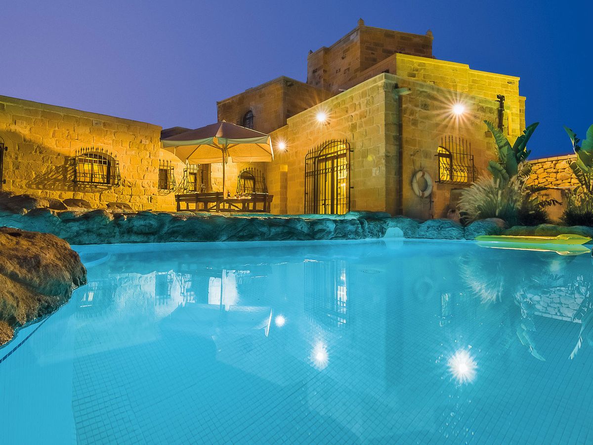 The Chateau's lake-style pool lit up at dusk