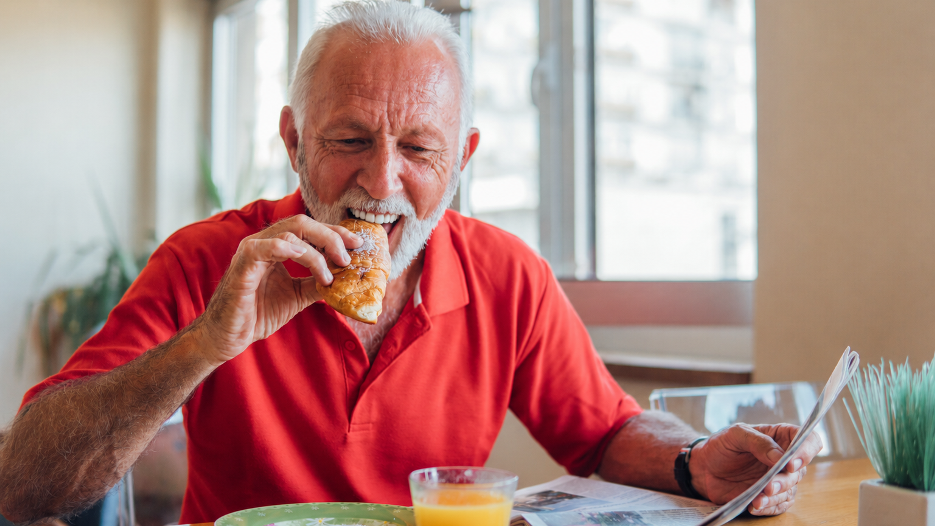 Smiling older man eating breakfast comfortably after researching dental implants on the NHS