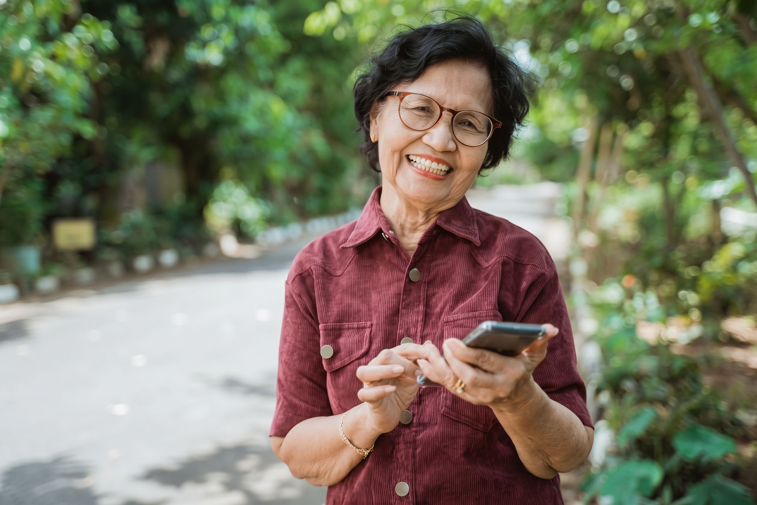 Smiling woman checking her phone for questions to ask about dental implants before choosing a clinic