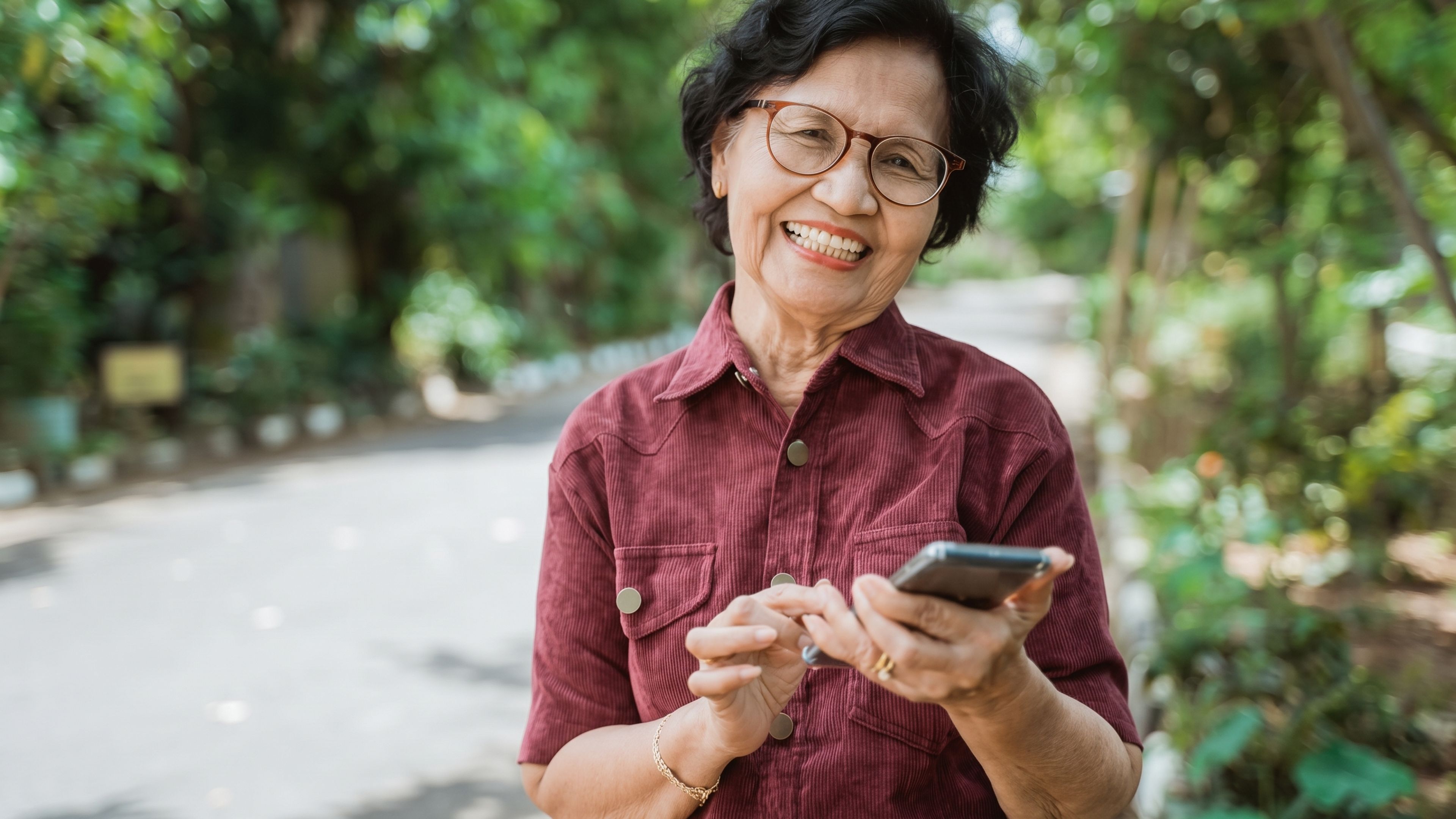Smiling woman checking her phone for questions to ask about dental implants before choosing a clinic