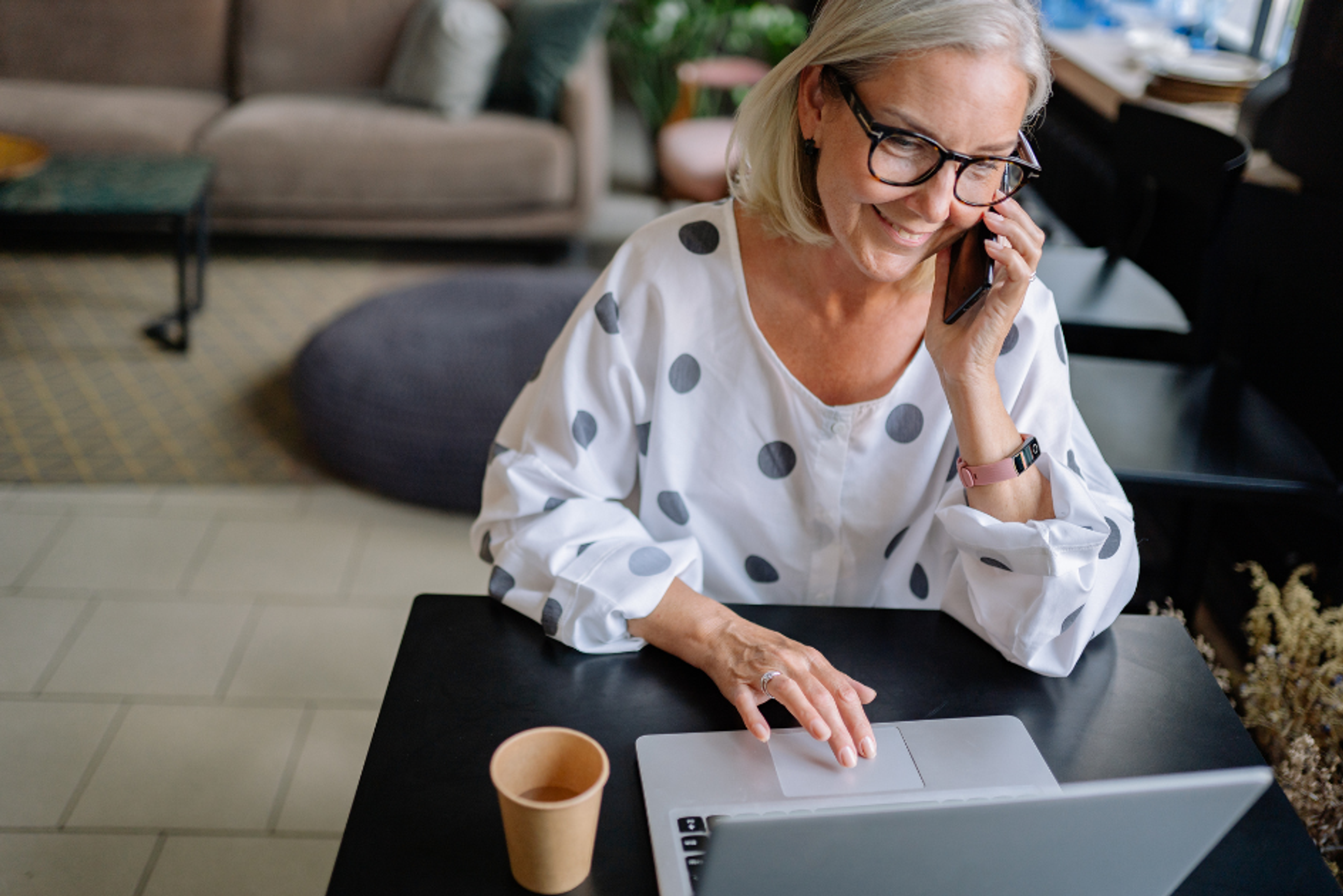 Woman on the phone at her laptop, comparing dental implant quotes from UK providers
