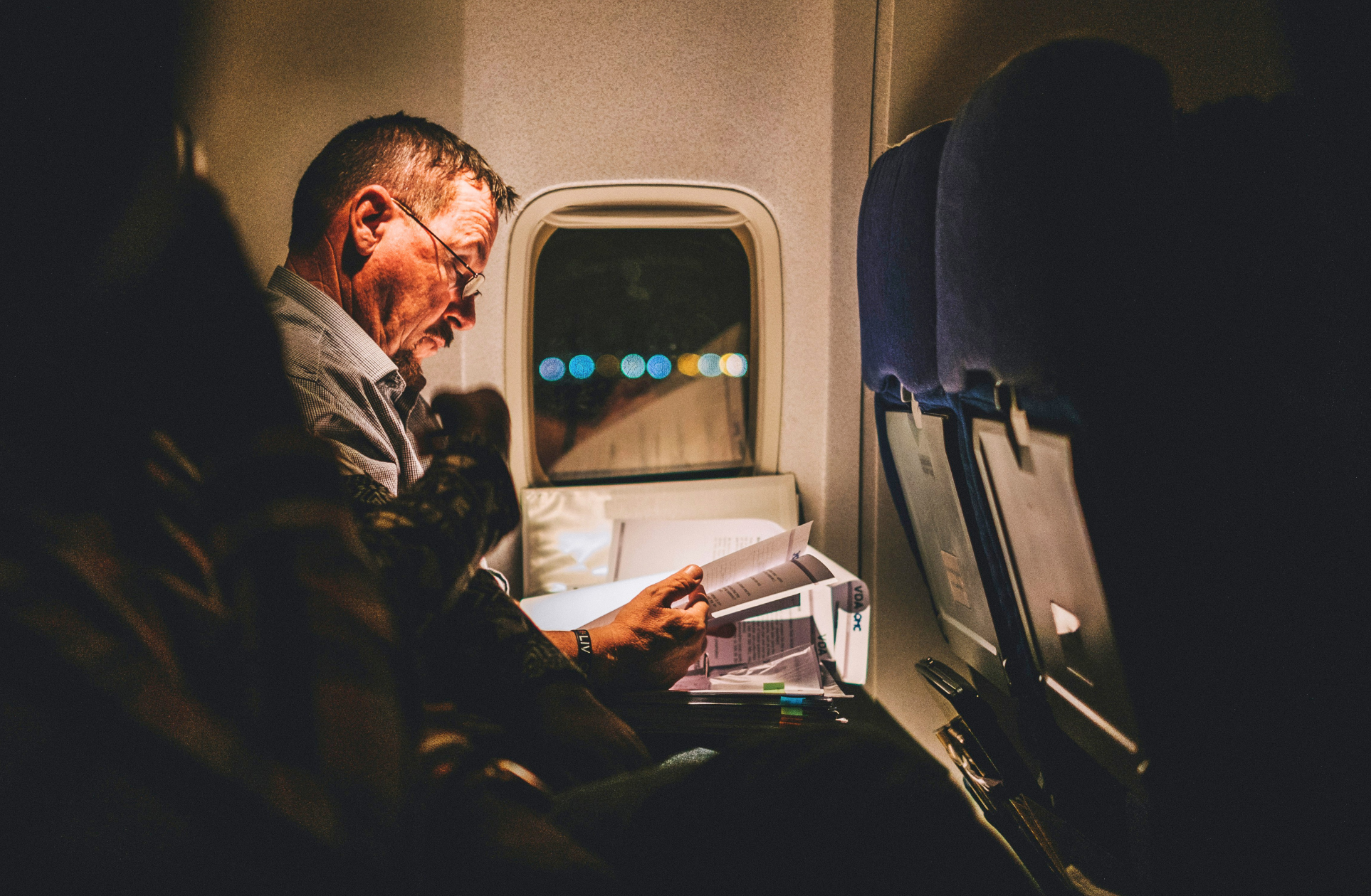 Older UK patient on a flight reading paperwork while considering dental implants in Turkey