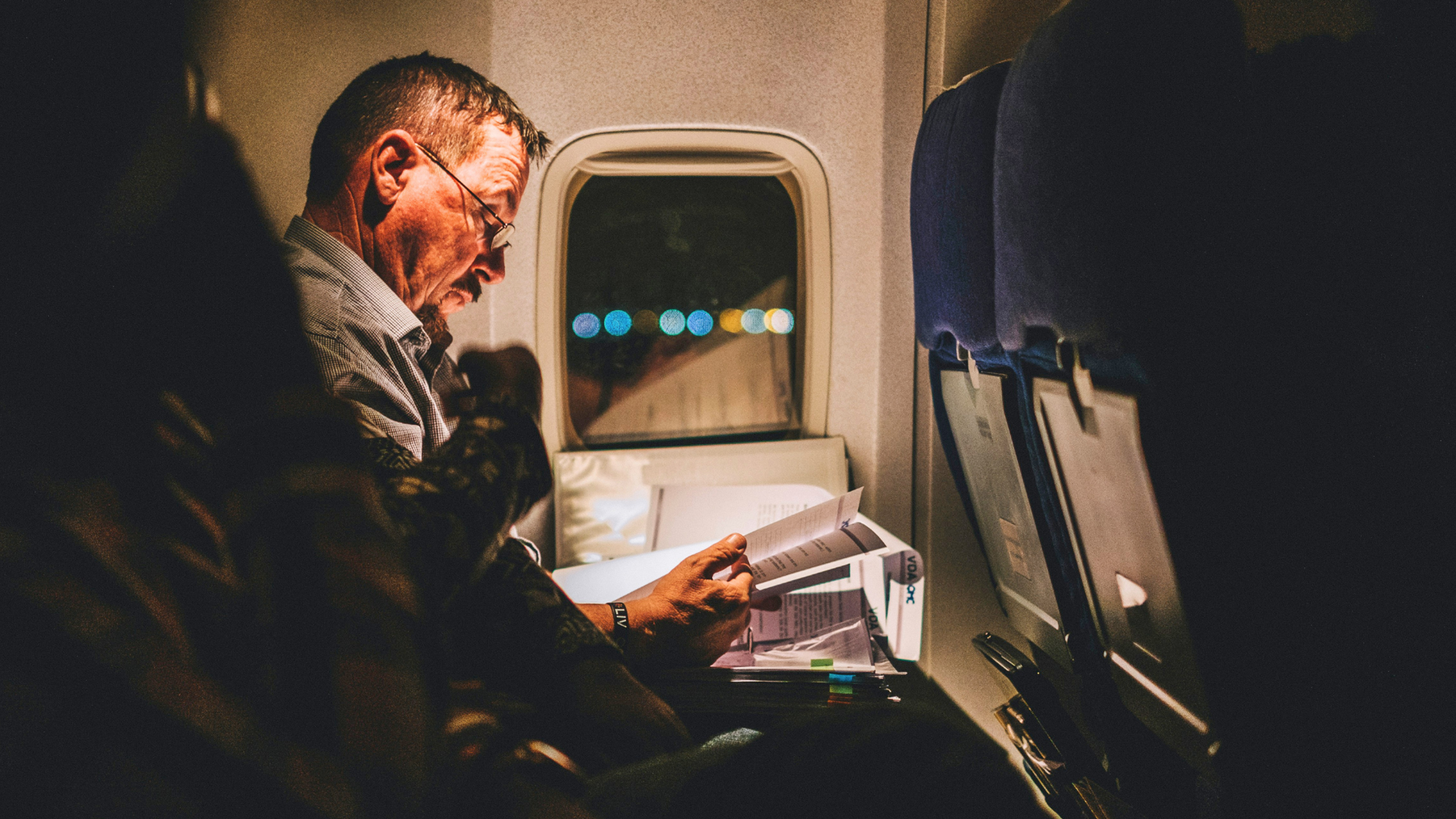 Older UK patient on a flight reading paperwork while considering dental implants in Turkey
