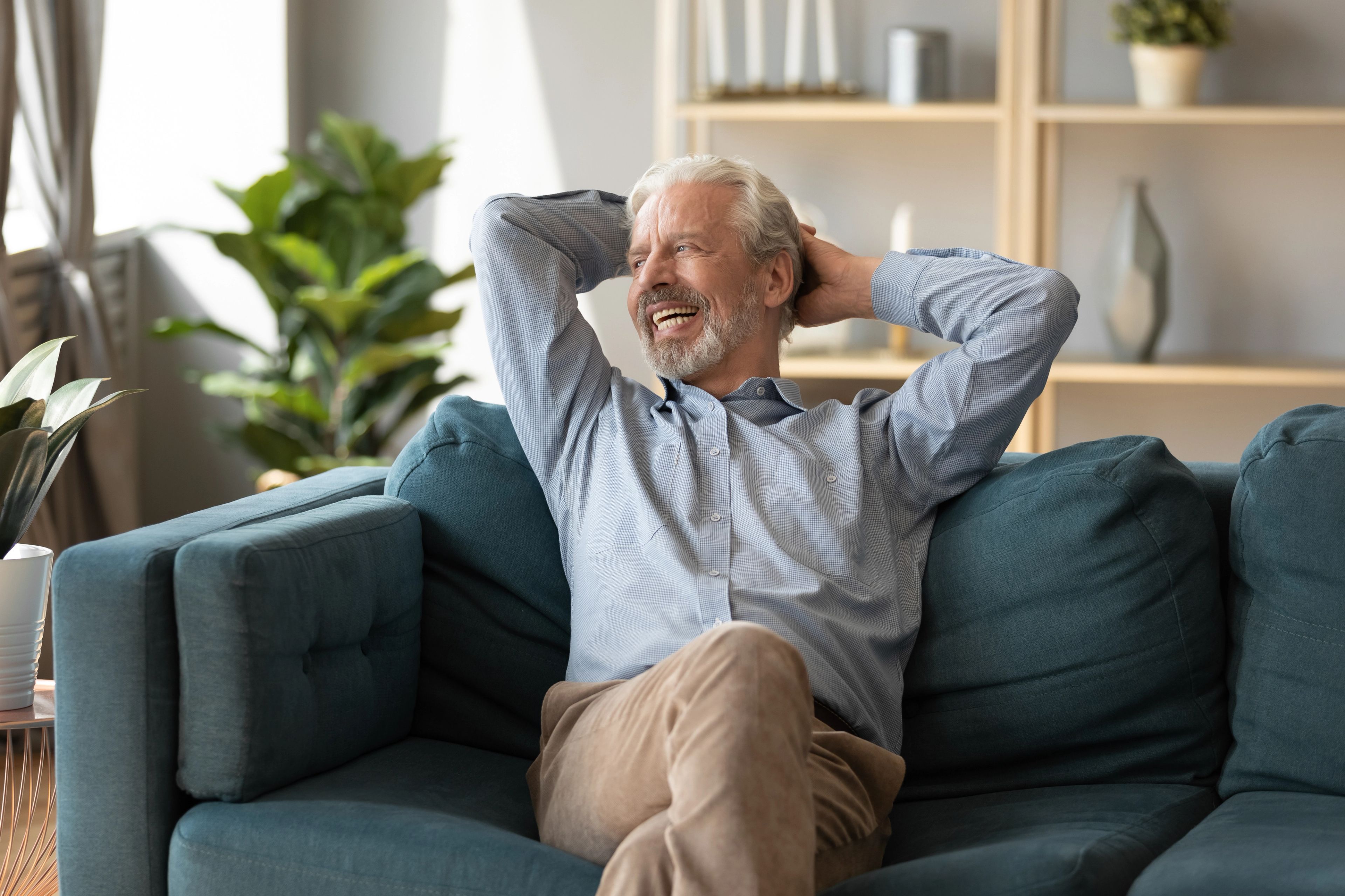 Relaxed older man at home comparing private dental implant costs with NHS options