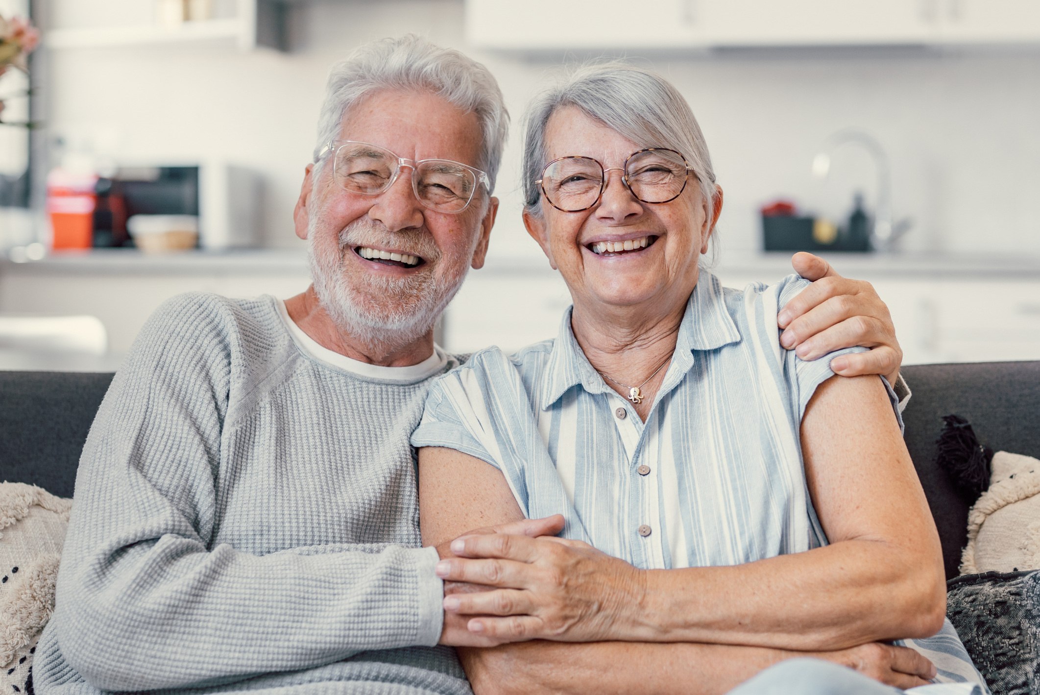 Smiling older couple at home after dental implant treatment with Safe Smile Implants UK