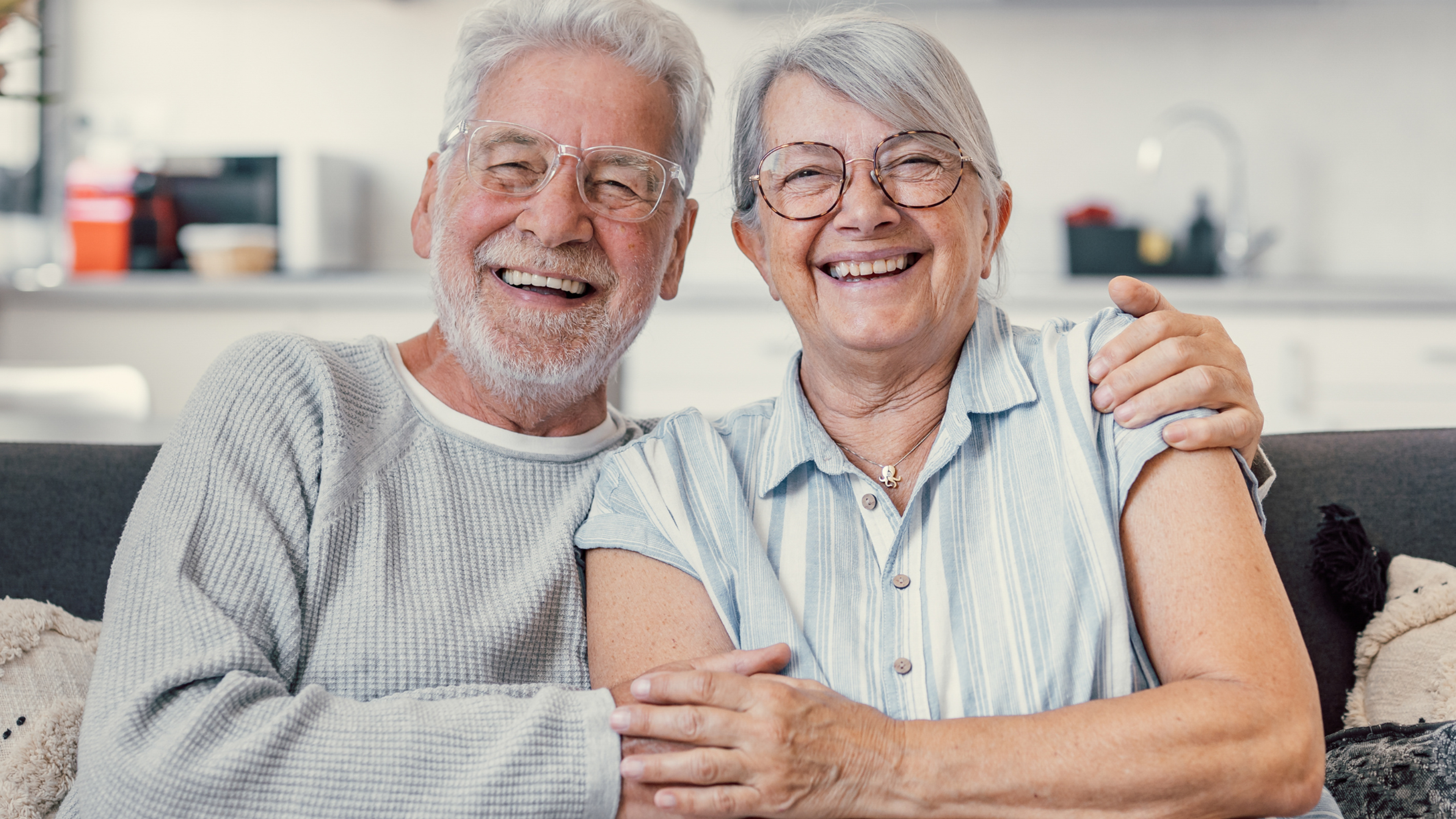 Smiling older couple at home after dental implant treatment with Safe Smile Implants UK