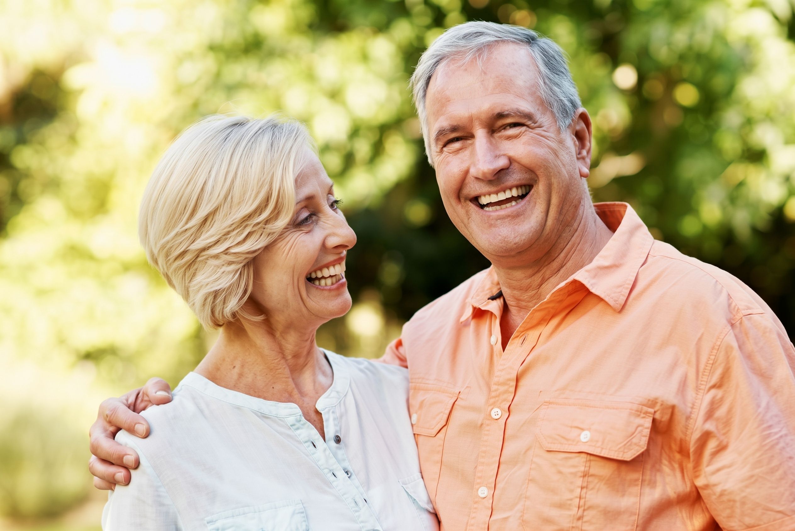 Smiling older couple laughing outdoors, a guide to why dental implants are so expensive in the UK