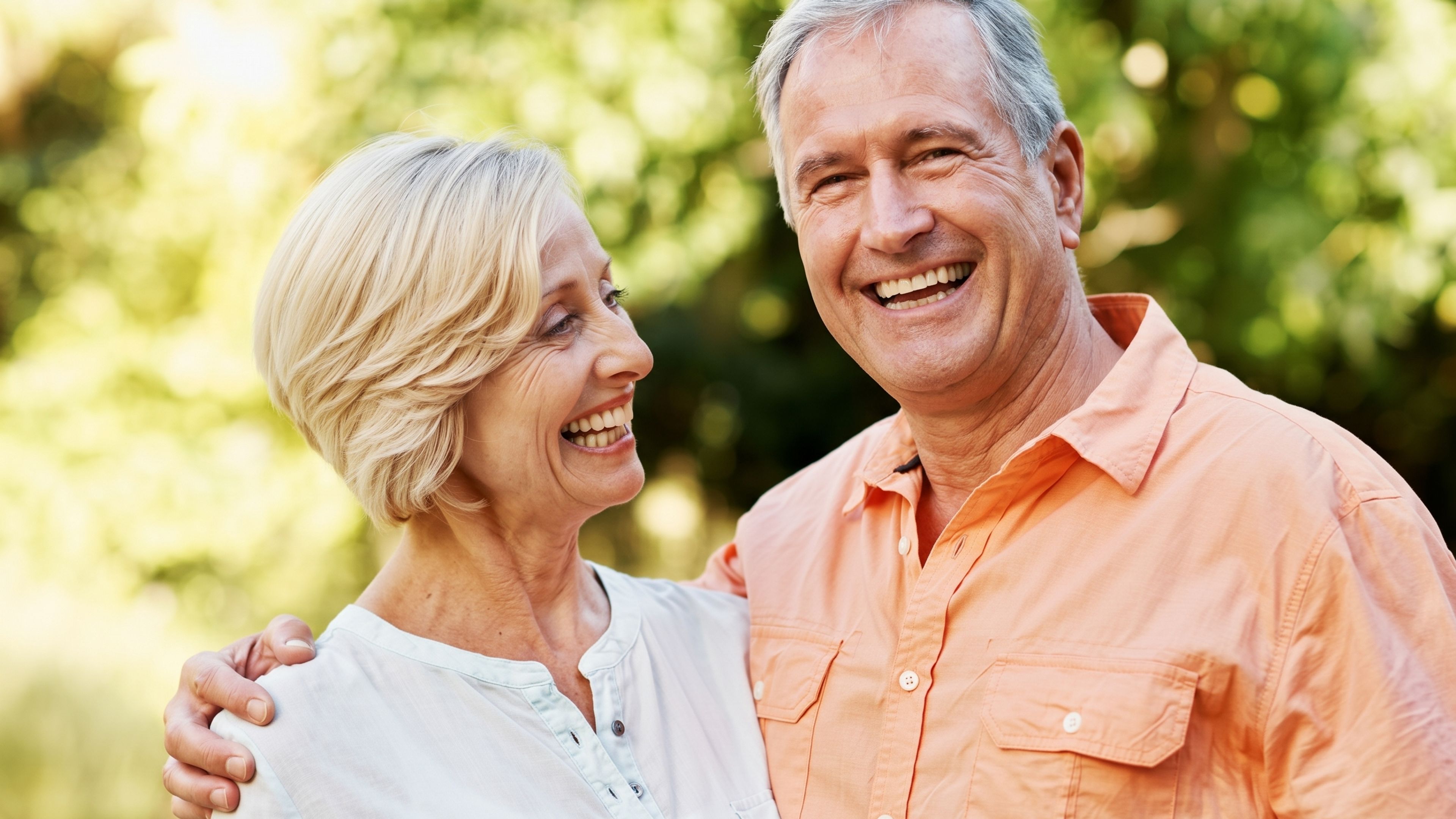 Smiling older couple laughing outdoors, a guide to why dental implants are so expensive in the UK