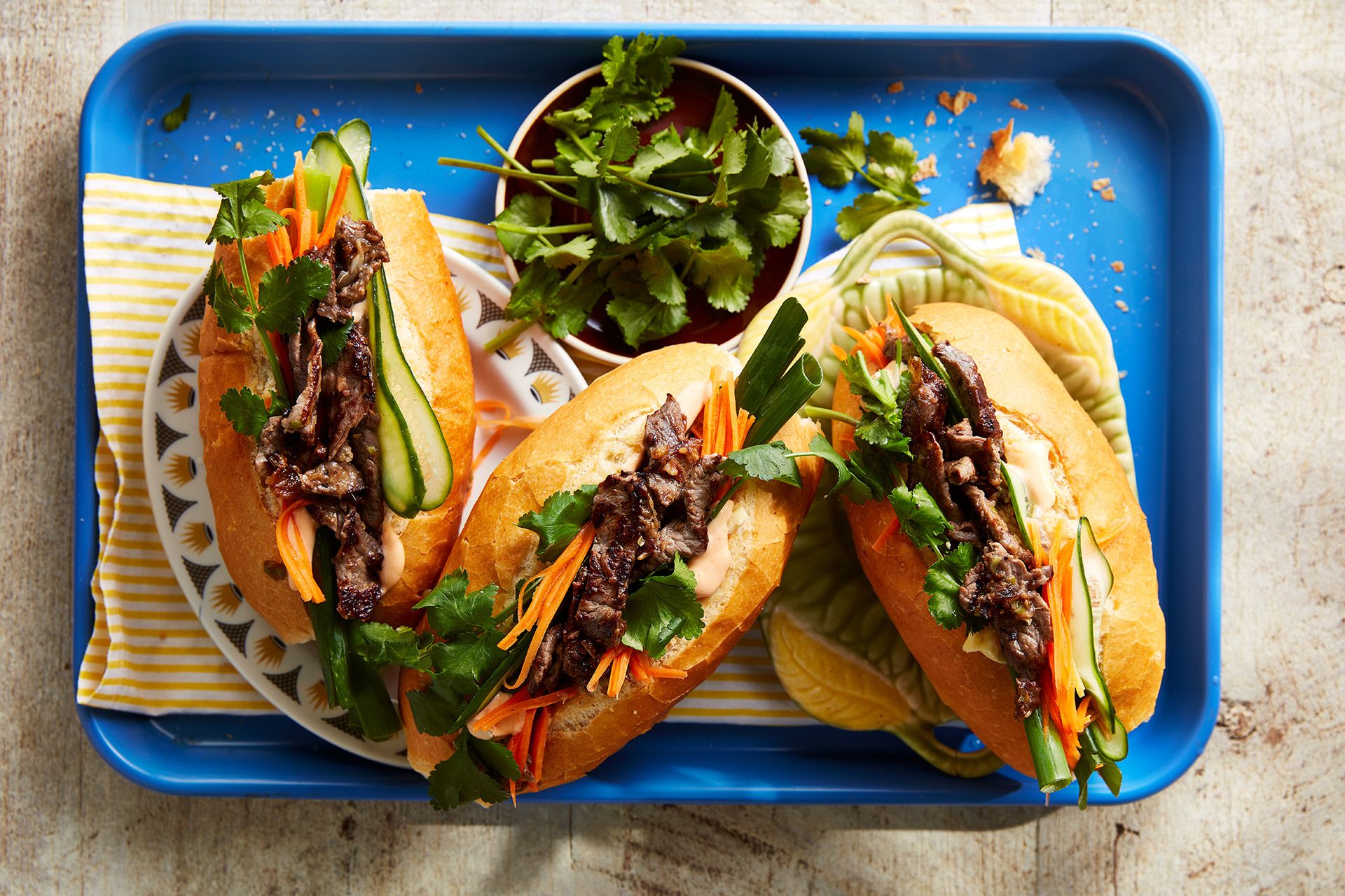 3 Bahn Mi roles on a tray with bowl of coriander