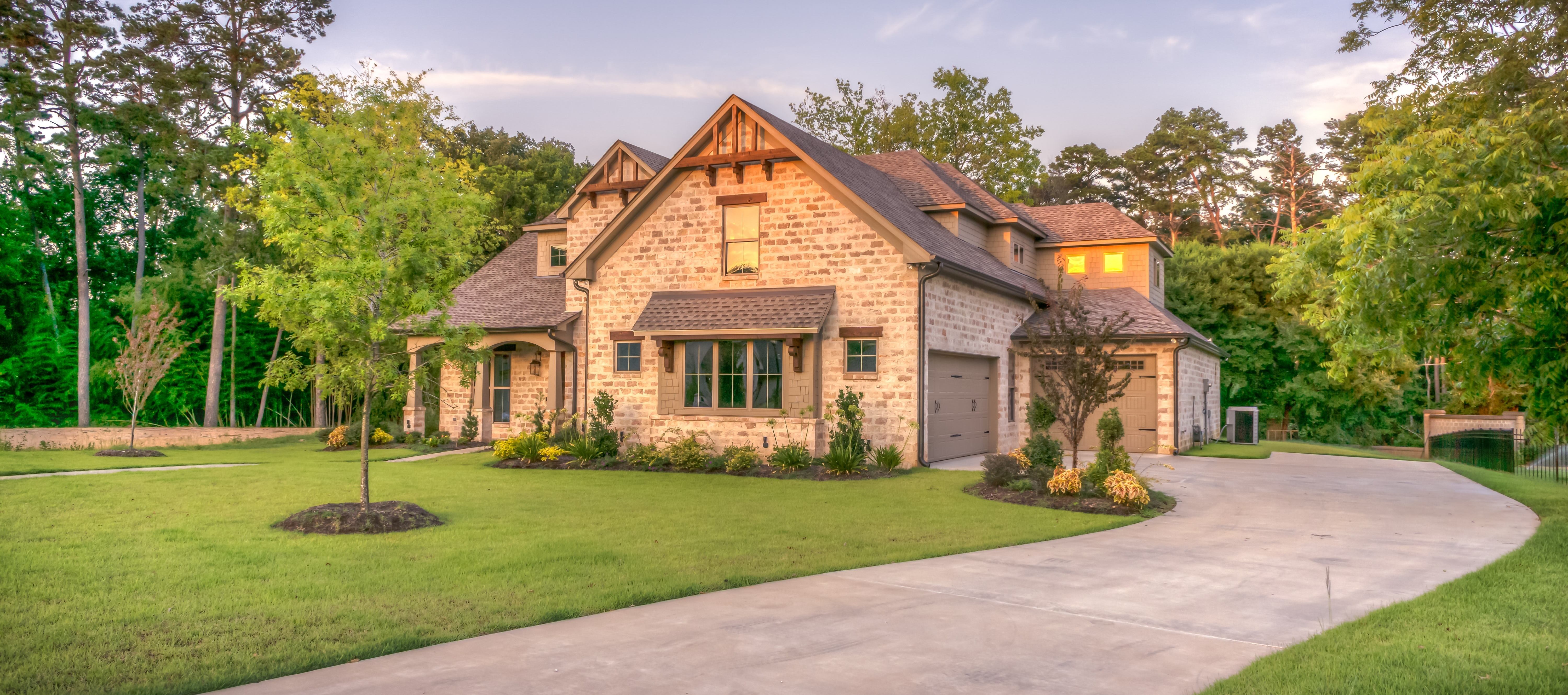 Light brown house with many trees behind it
