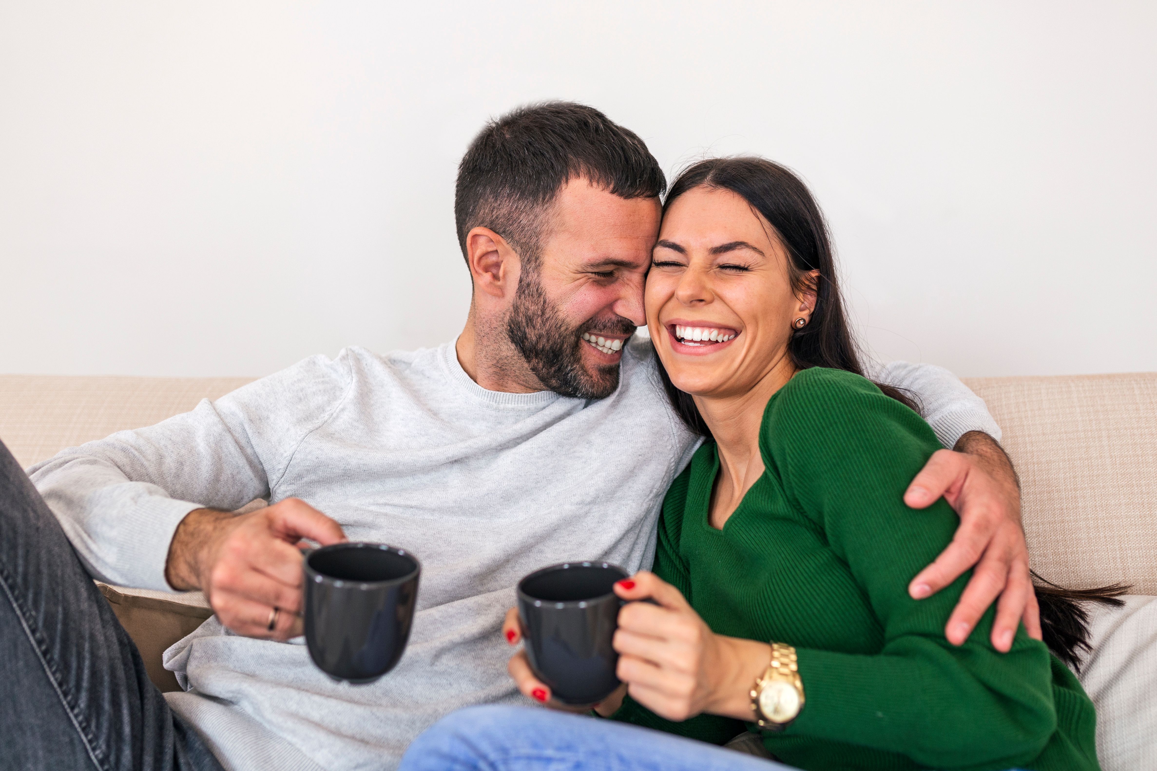 Couple sitting on couch with coffee mugs
