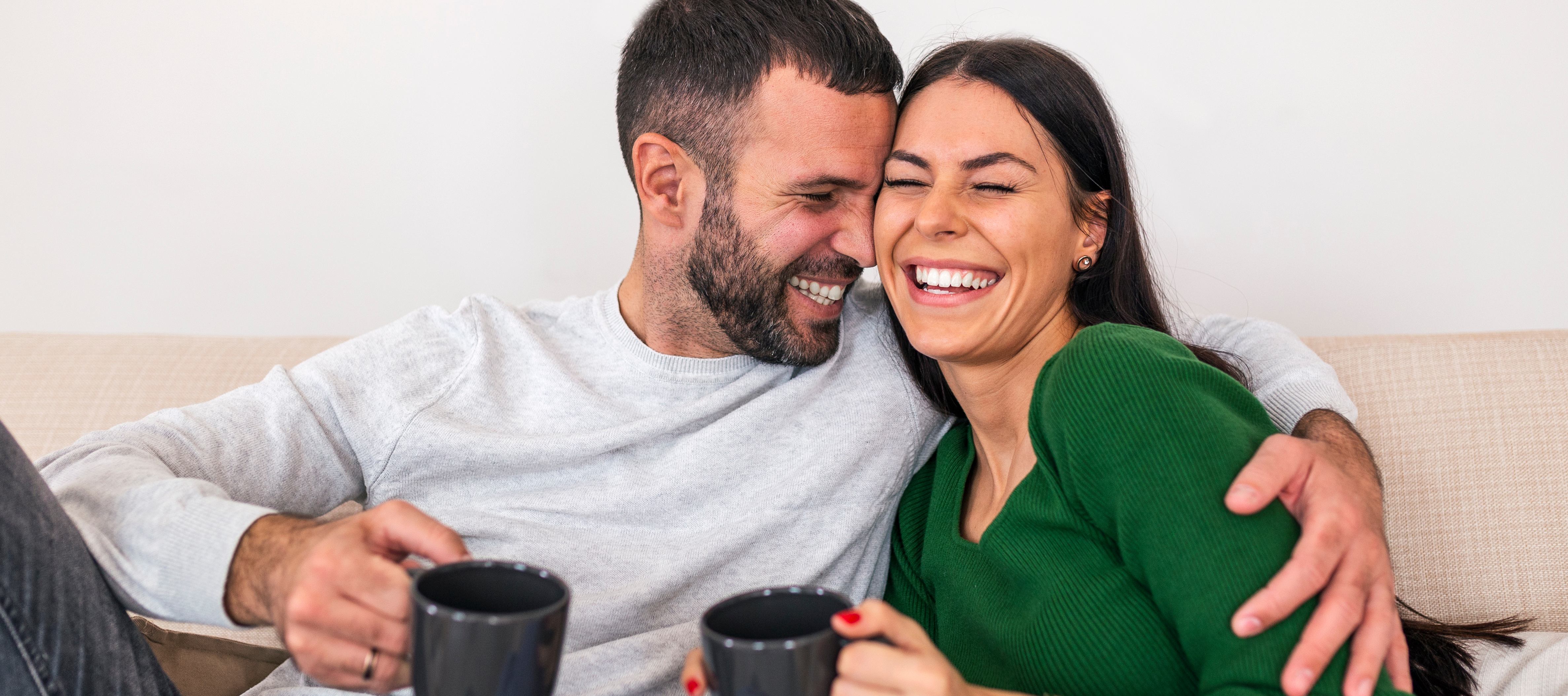 Couple sitting on couch with coffee mugs