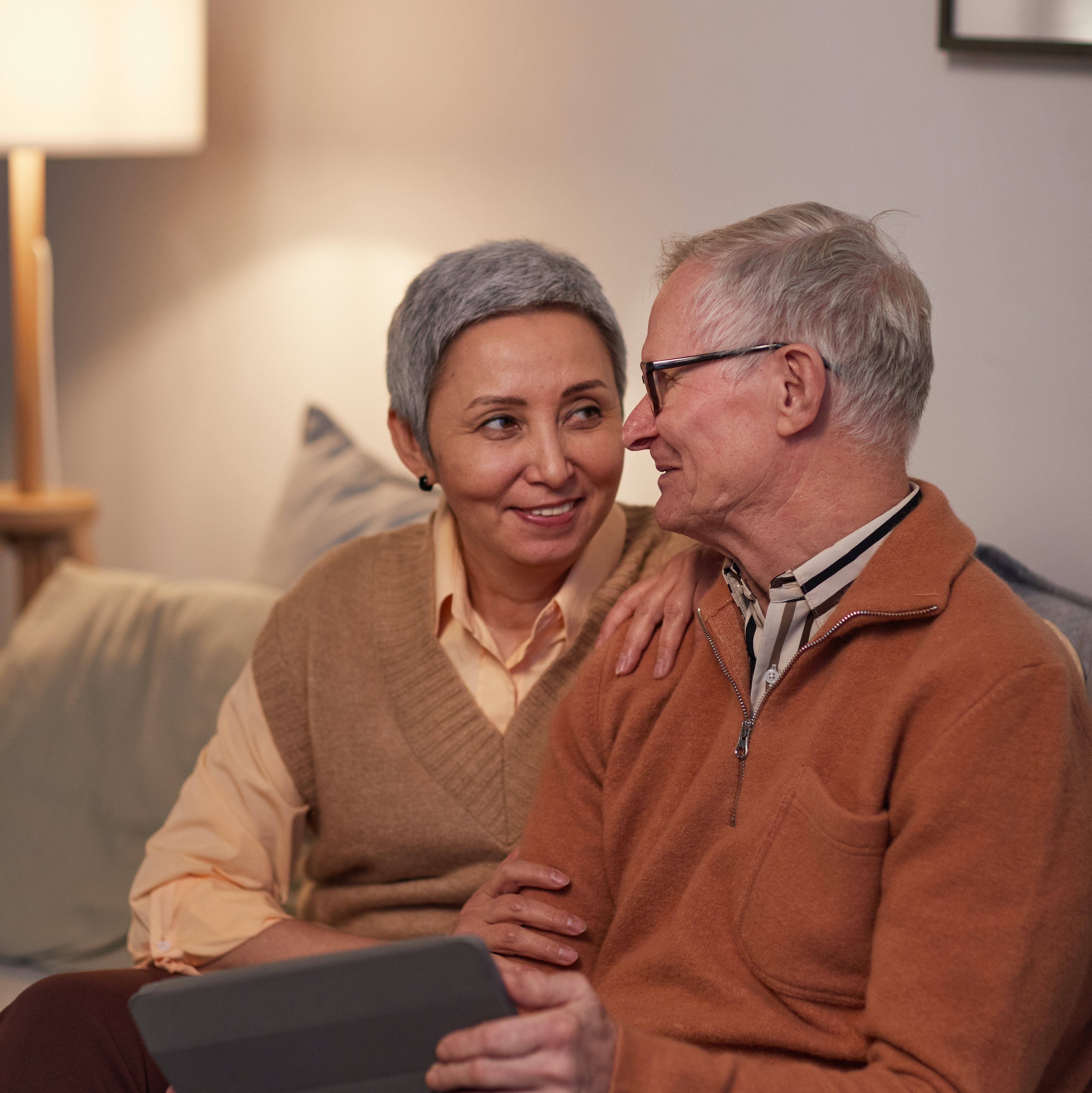 Older couple sitting on couch looking at picture frame