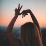 A woman making a peace sign with her hands.