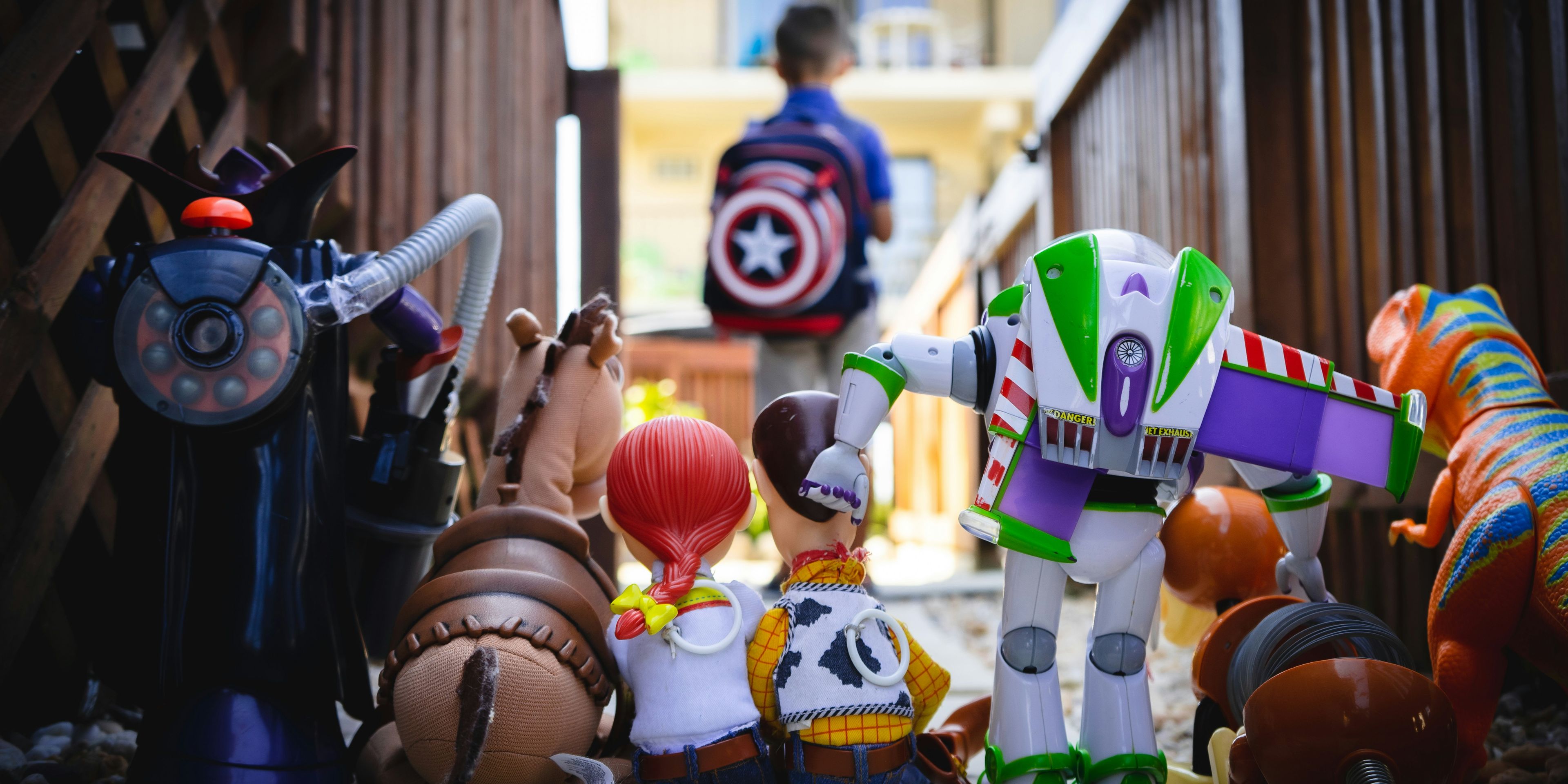 A boy with a Captain America backpack is standing in front of a group of Toy Story characters.