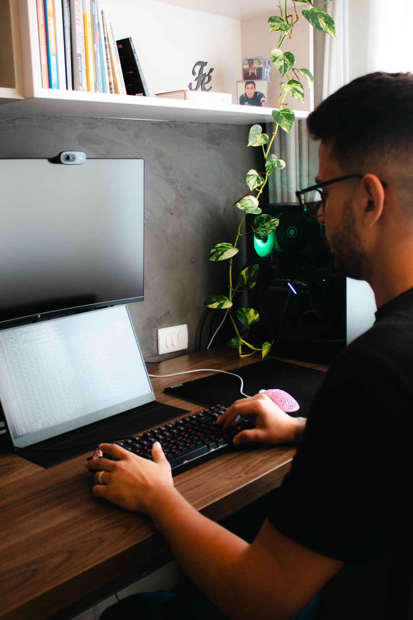 Homem jovem trabalhando no home office, com notebook e monitor