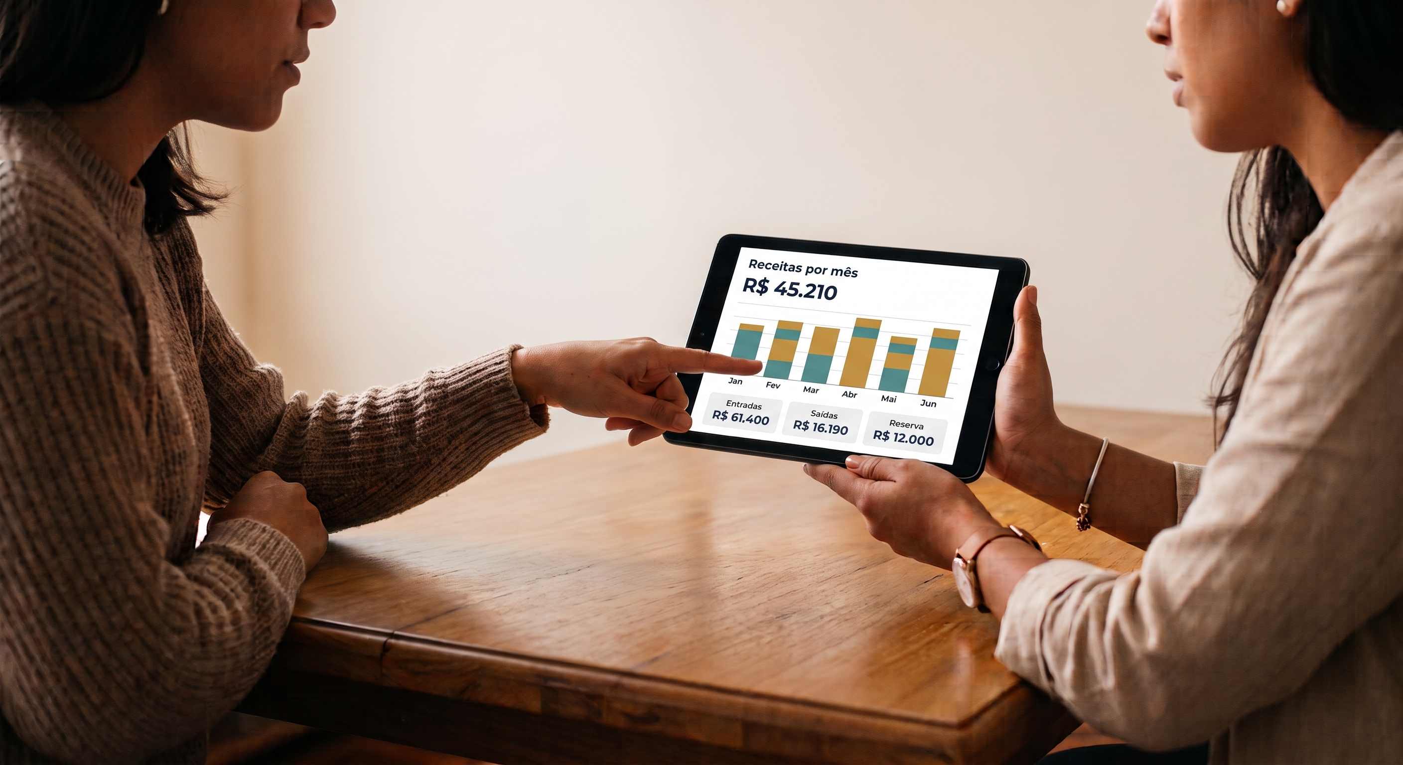 Duas profissionais analisando gráfico de receitas mensais da conta PJ em tablet