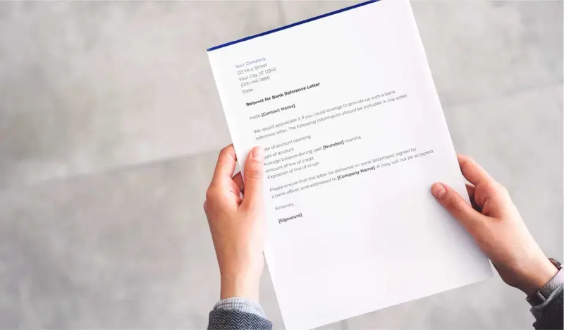 A man holds a mock-up of a bank reference letter to be completed by a bank.