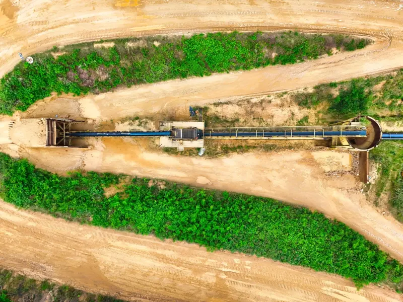 Aerial image of an industrial conveyor system between green fields.