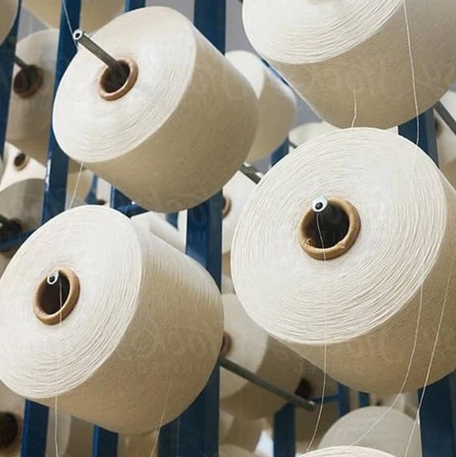 Cones of white yarn mounted on a textile mill frame