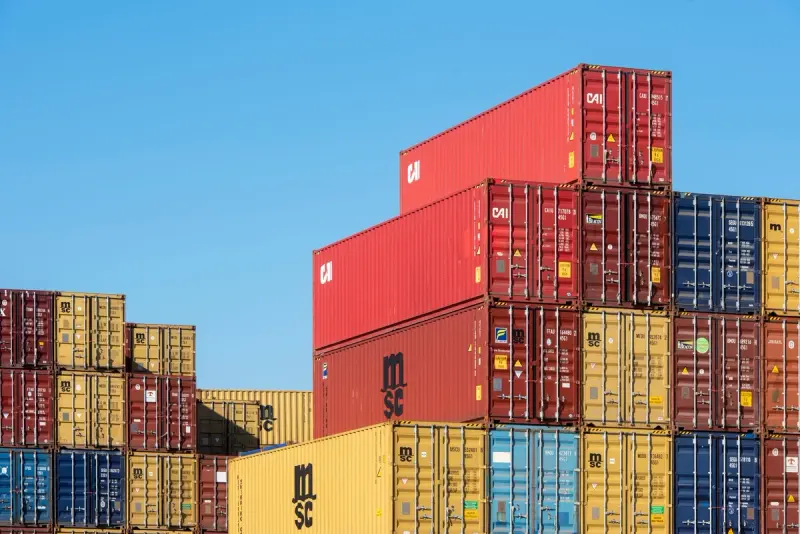 Stacked shipping containers under a clear blue sky